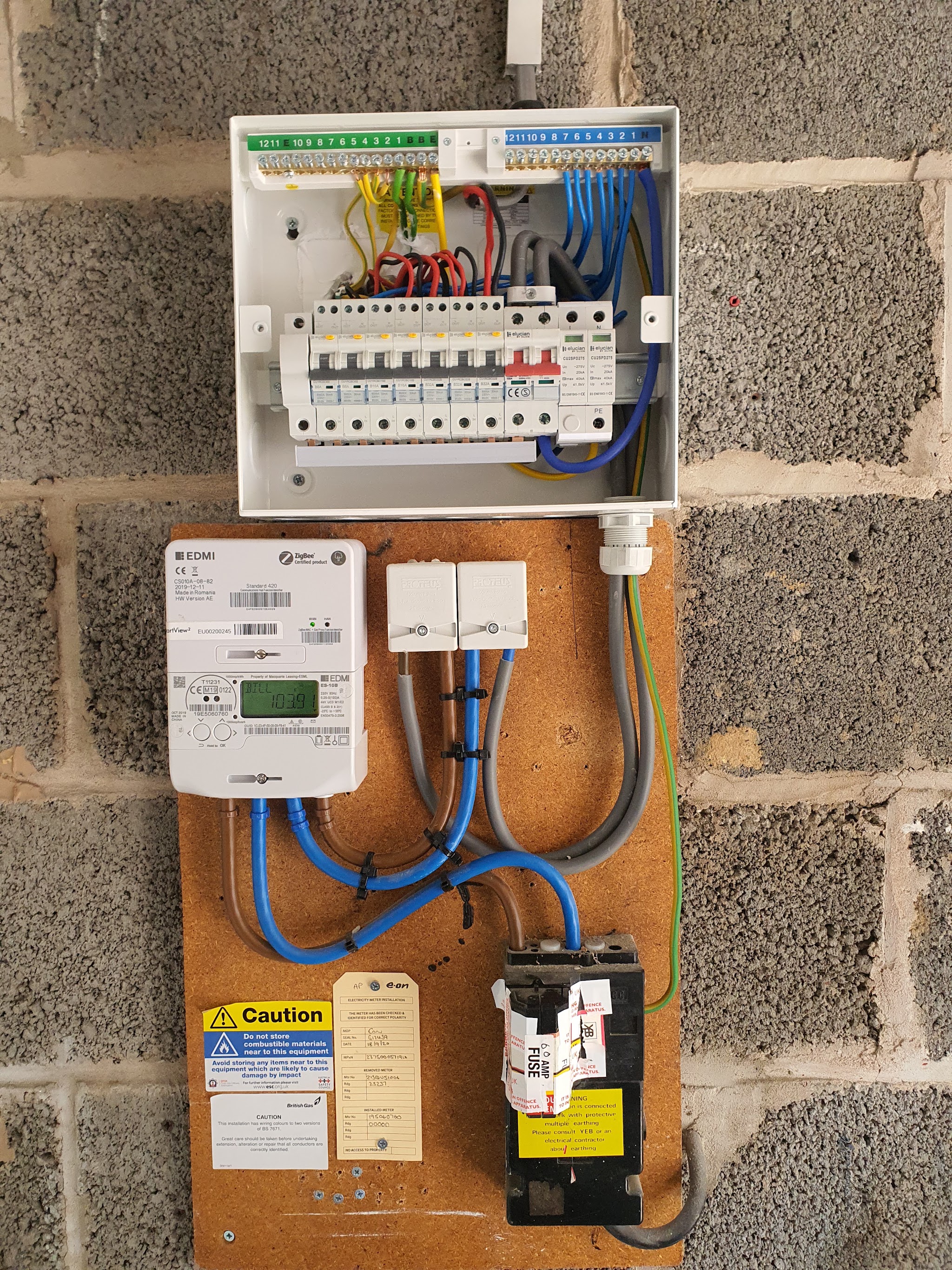 A newly fitted consumer unit, meters and isolator mounted on a blockwork wall