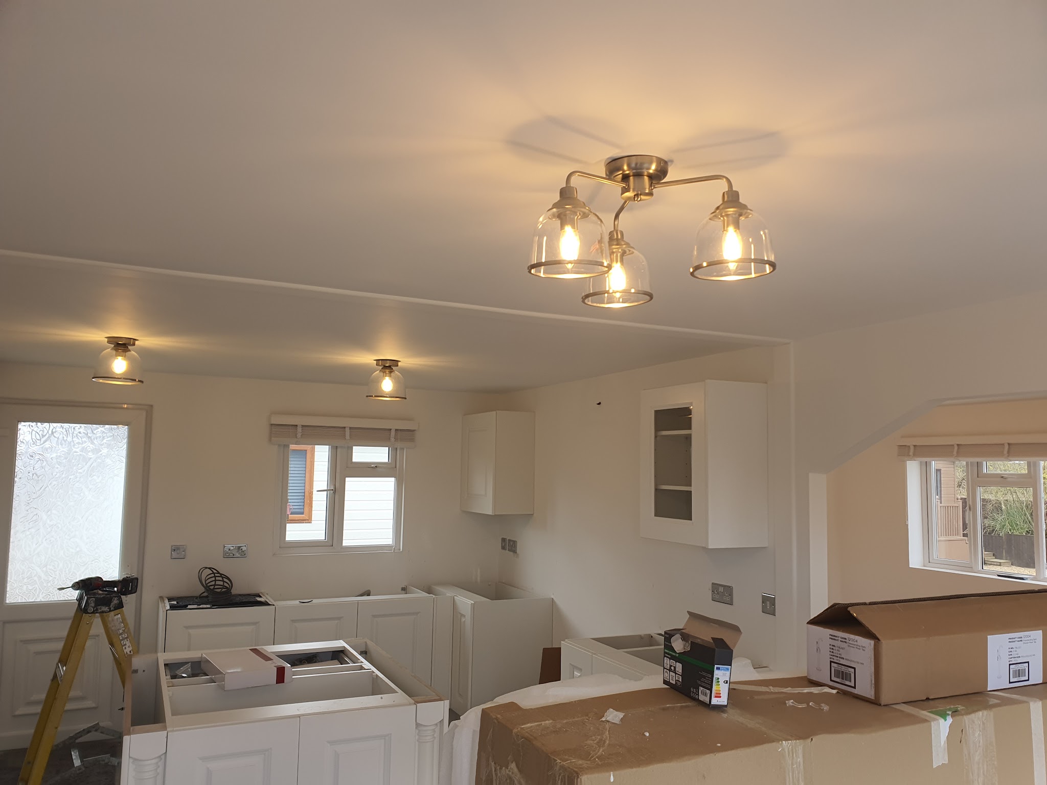 A kitchen mid-fit with a new three-light ceiling fitting and downlights