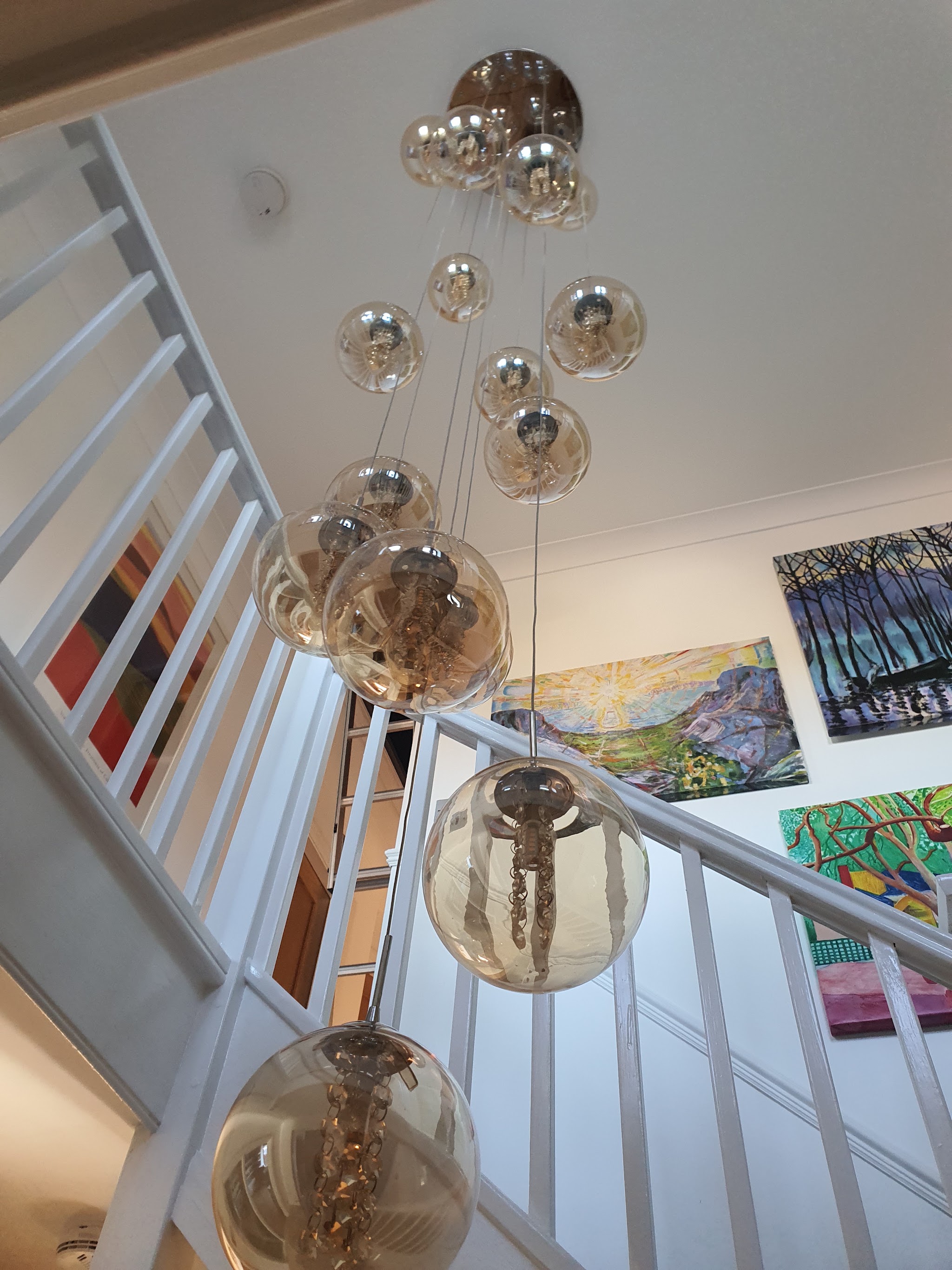 A cluster of smoked glass globe pendants hanging down a white stairwell