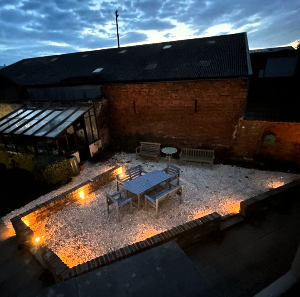 A courtyard garden at dusk lit by low wall lights