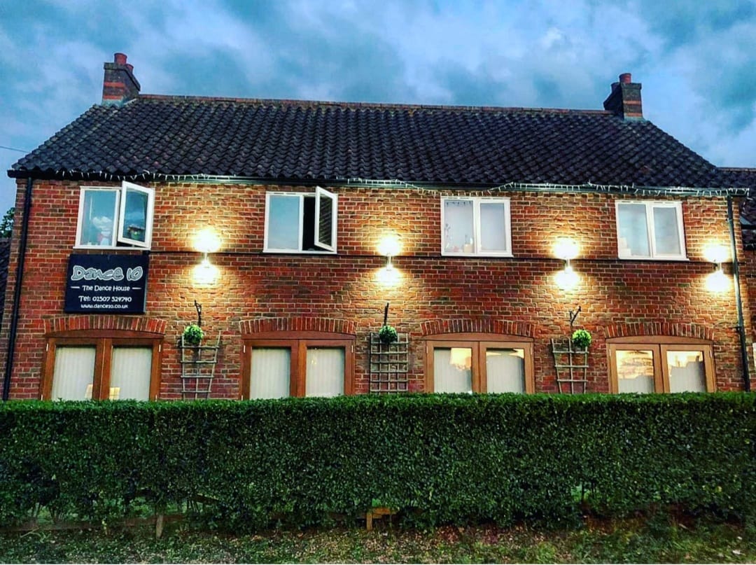 A brick building at dusk with a row of up and down wall lights