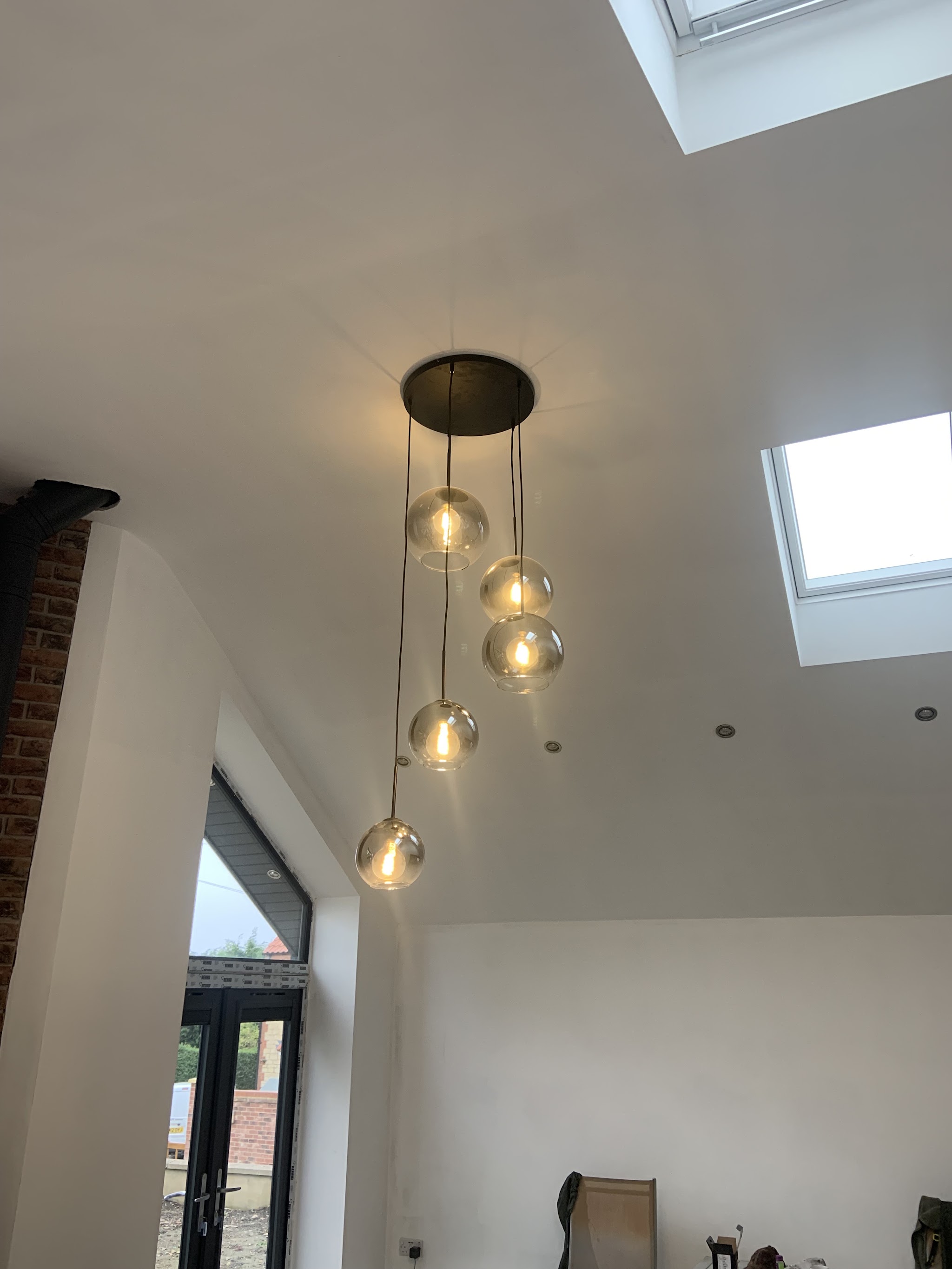 A vaulted room with a cluster pendant light and skylights