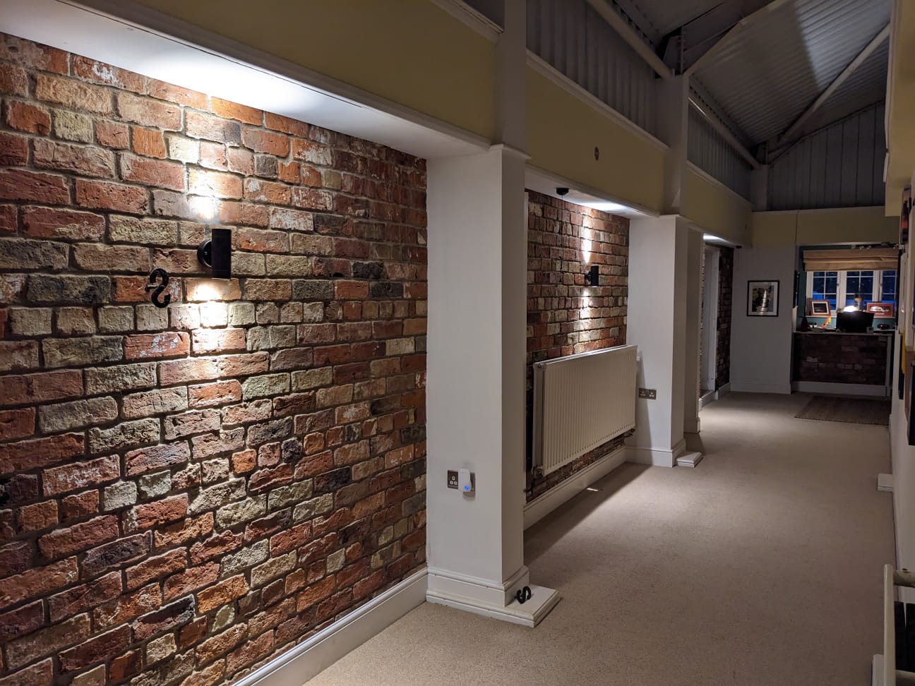 A barn conversion corridor with exposed brick and wall lights